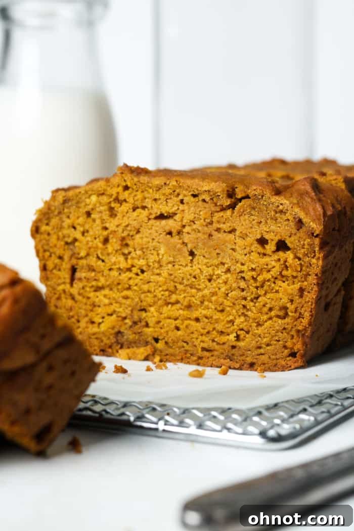 Golden brown loaf of gluten-free pumpkin bread on a wire rack.