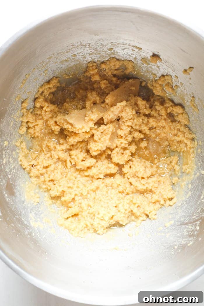 Runny cookie batter with wet ingredients added in a mixing bowl.