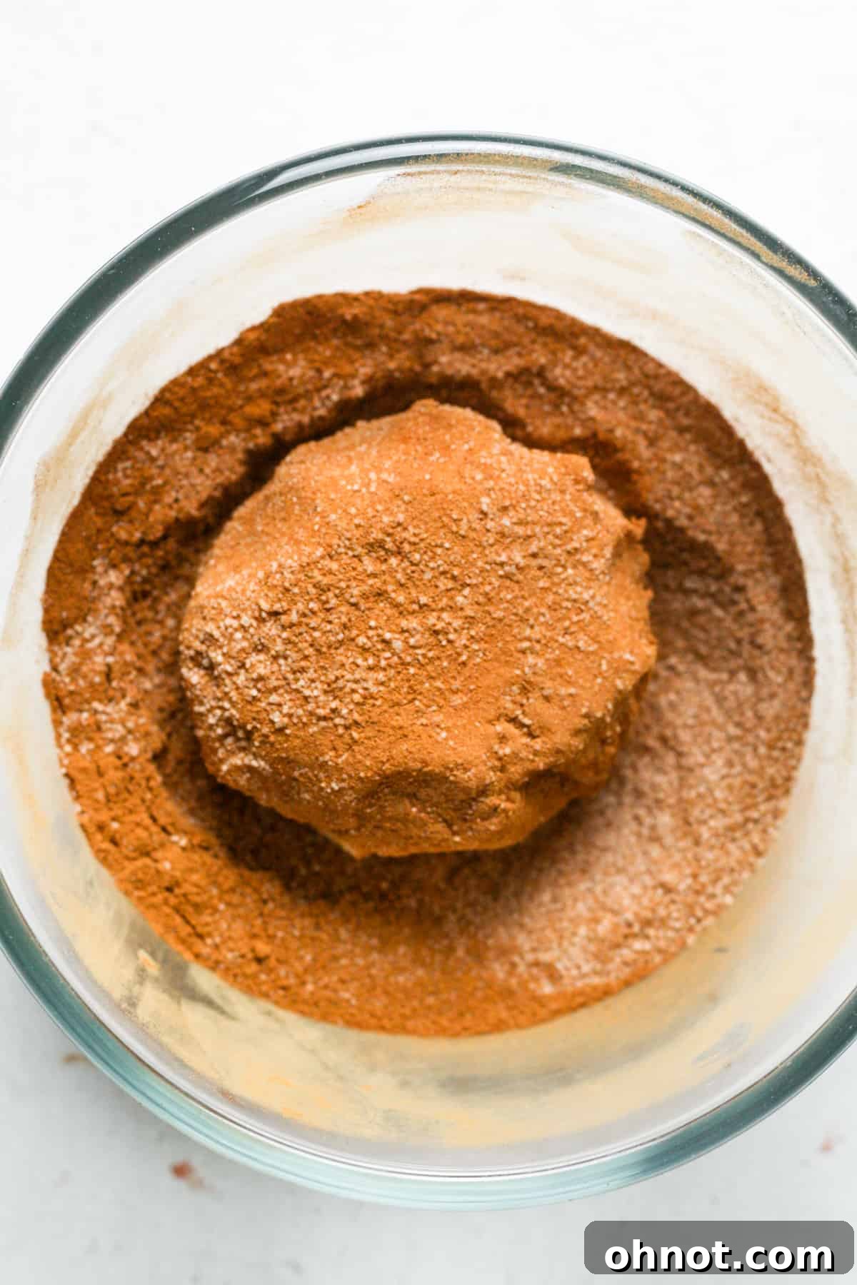 A perfectly coated cinnamon sugar cookie dough ball ready for baking.