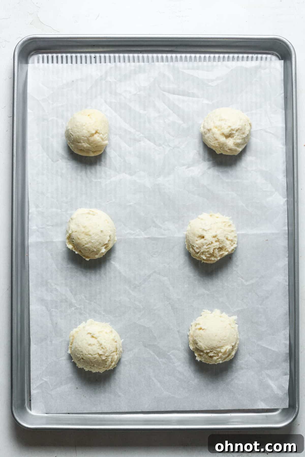 Scooped balls of cookie dough on a baking pan before coating.