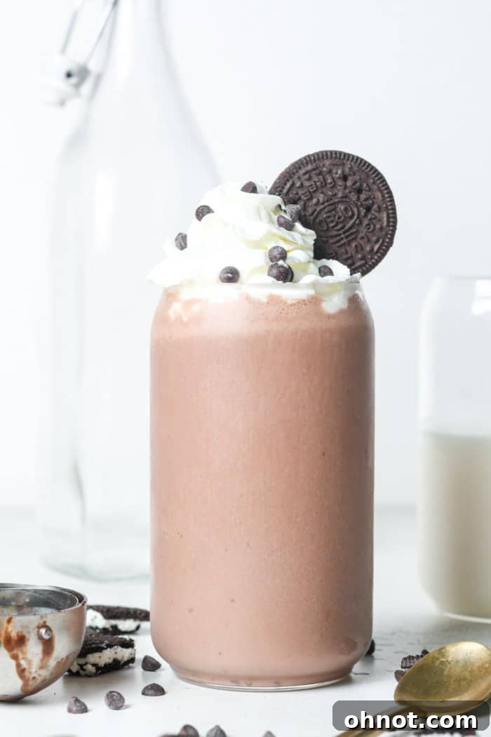 Thick and creamy vegan milkshake served in a tall glass, garnished with vegan whipped cream and a sprinkle of chocolate shavings.