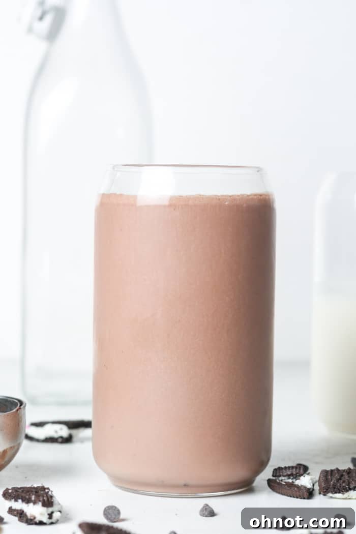 A tall glass filled with a rich vegan chocolate drink, possibly a milkshake, showcasing its smooth texture.