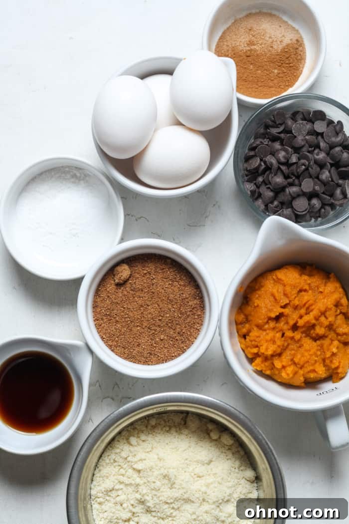 Assortment of fresh baking ingredients laid out for making pumpkin bread, including eggs, pumpkin puree, and spices.