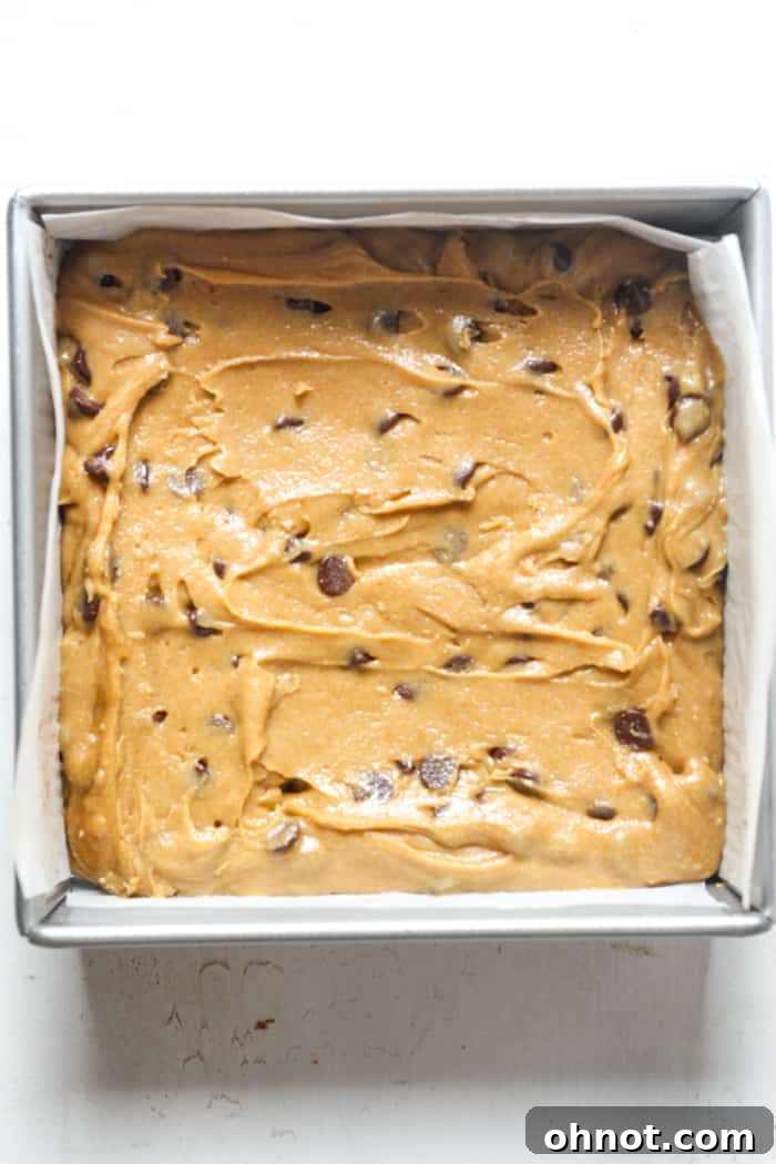 Blondie dough spread evenly in a square pan, ready to bake.