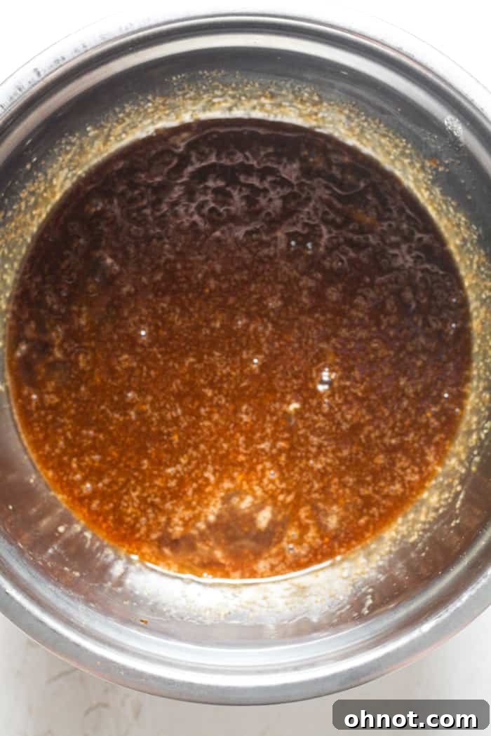 Dark brown, glossy blondie batter after eggs and vanilla have been added.