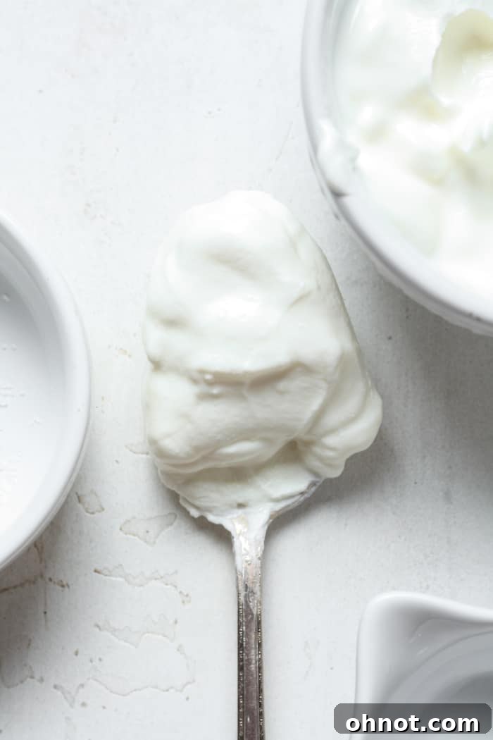 A spoon scooping out creamy dairy-free sour cream from a bowl.