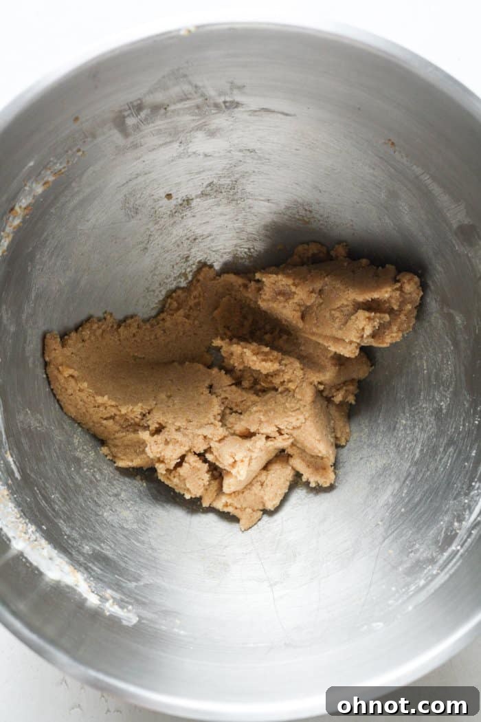 A bowl containing cold butter, granulated sugar, and brown sugar being creamed together.