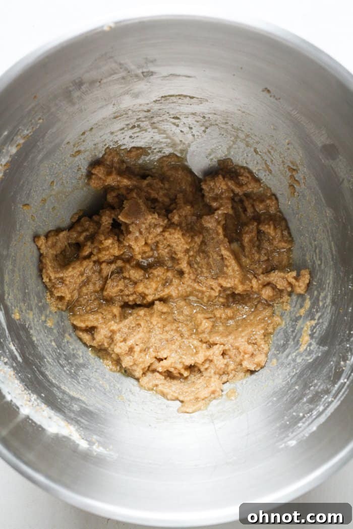 Light brown cookie dough in a mixing bowl after wet ingredients have been added.