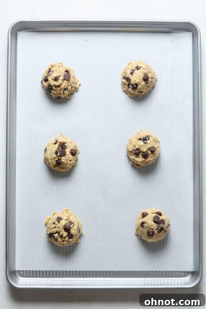 Evenly portioned balls of oatmeal cookie dough arranged on a baking sheet.