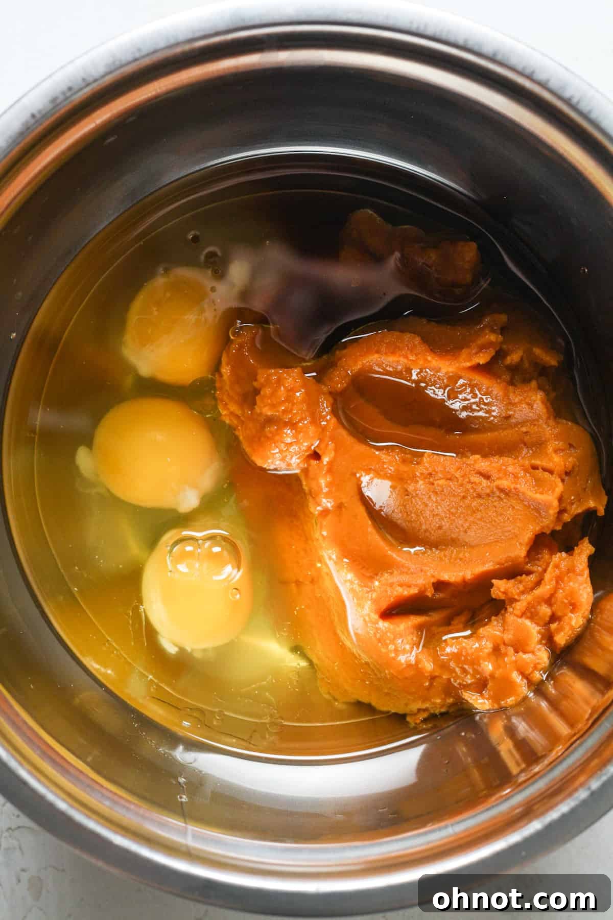Pumpkin puree and eggs being mixed in a bowl, showing the initial wet ingredients.