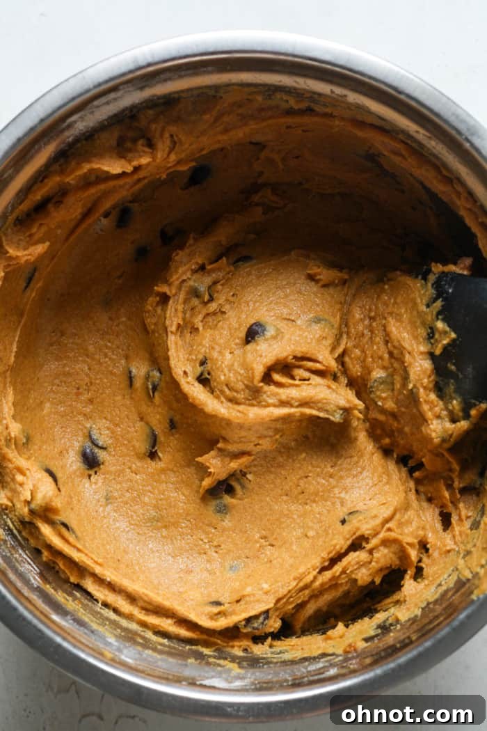 Pumpkin muffin batter with chocolate chips folded in, ready for baking.