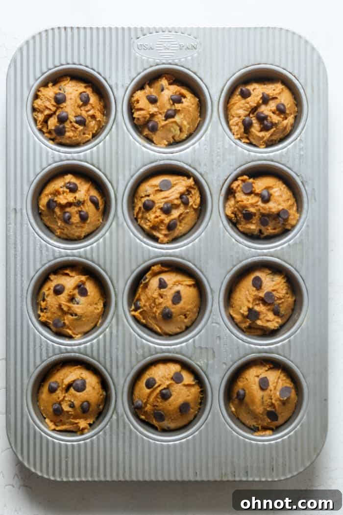 Muffin pan filled with raw pumpkin muffin batter, ready for the oven.