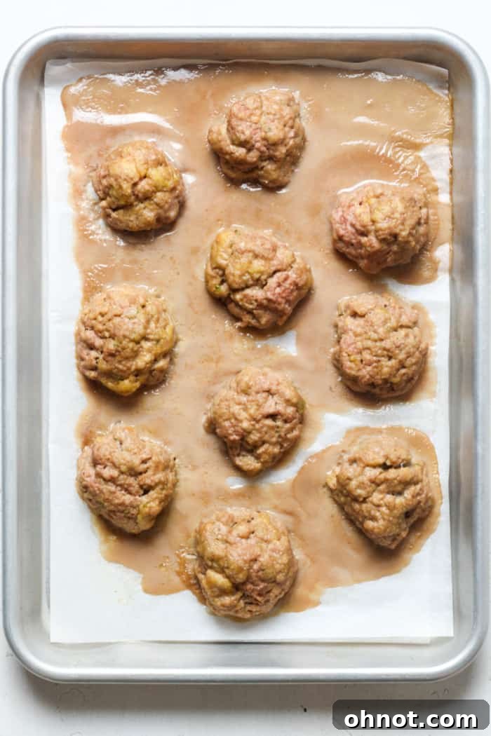 Baked turkey meatballs, golden brown and cooked, still on the baking pan.