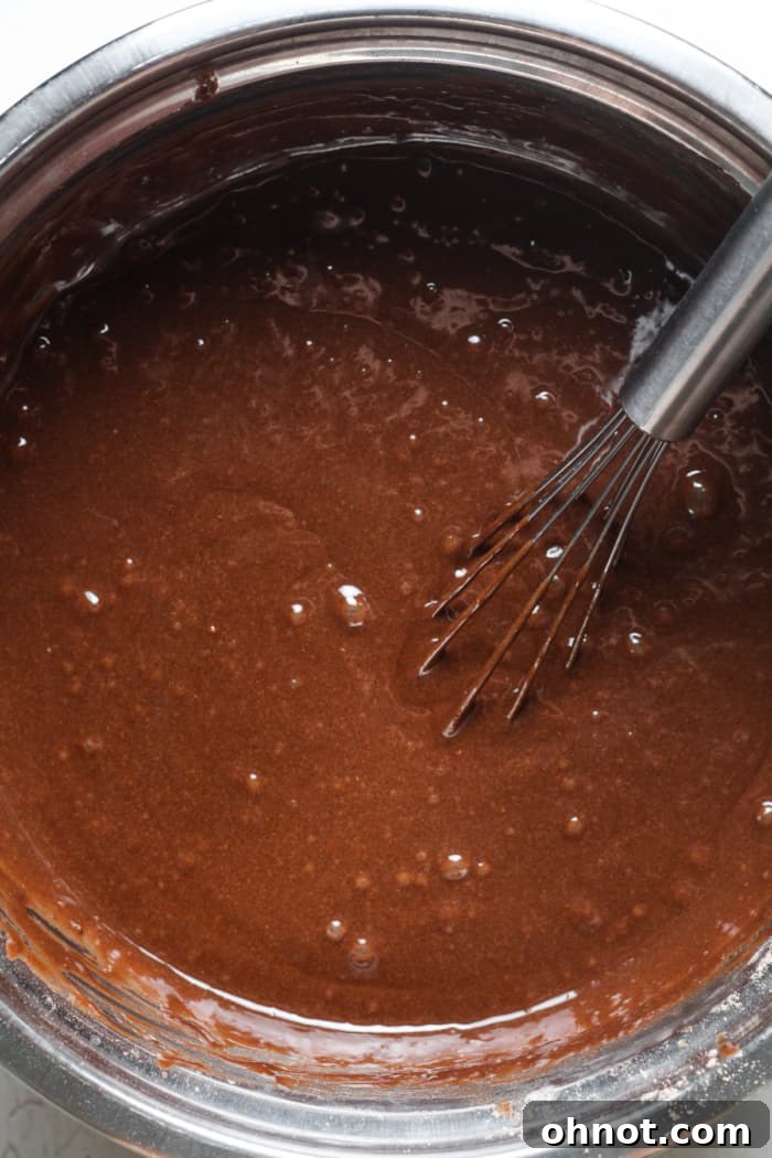 Thick, rich chocolate cake batter inside a large mixing bowl, ready for baking.