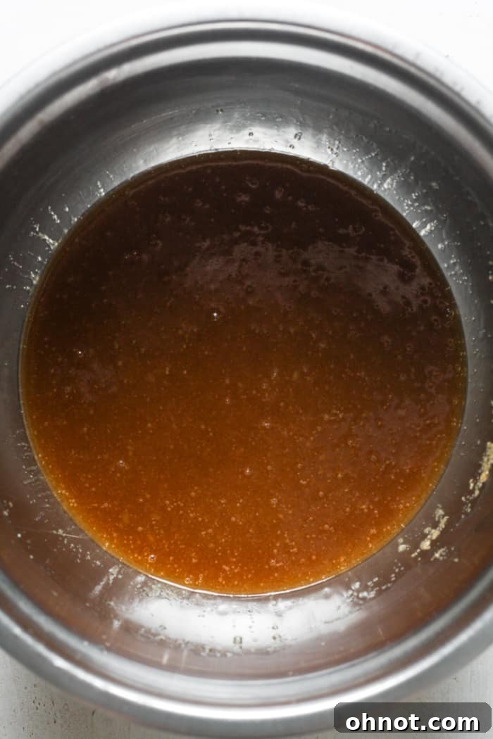 Dissolved butter and sugar with vanilla and applesauce in a bowl.