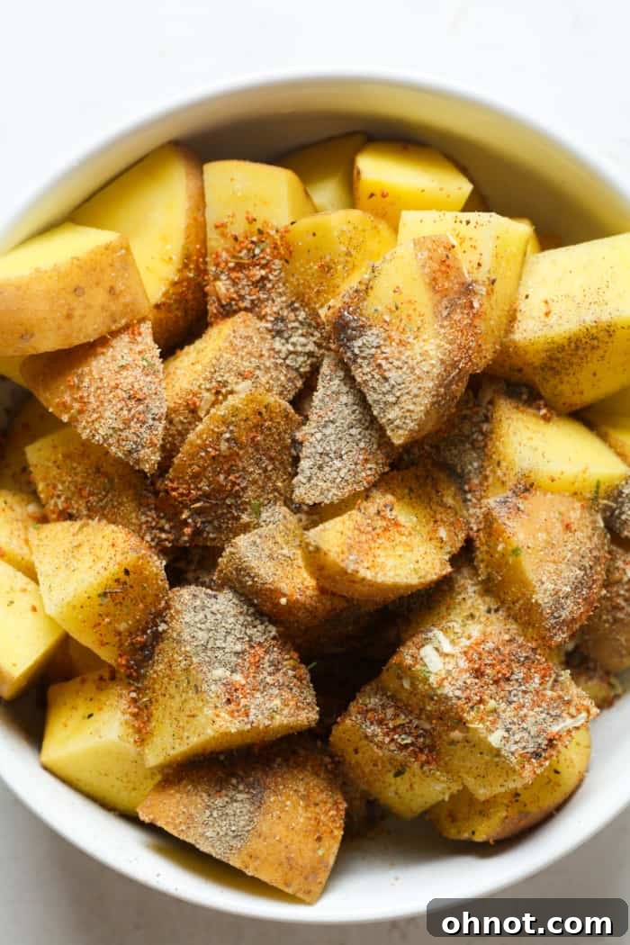 Cubed potatoes in a bowl, evenly coated with seasonings.