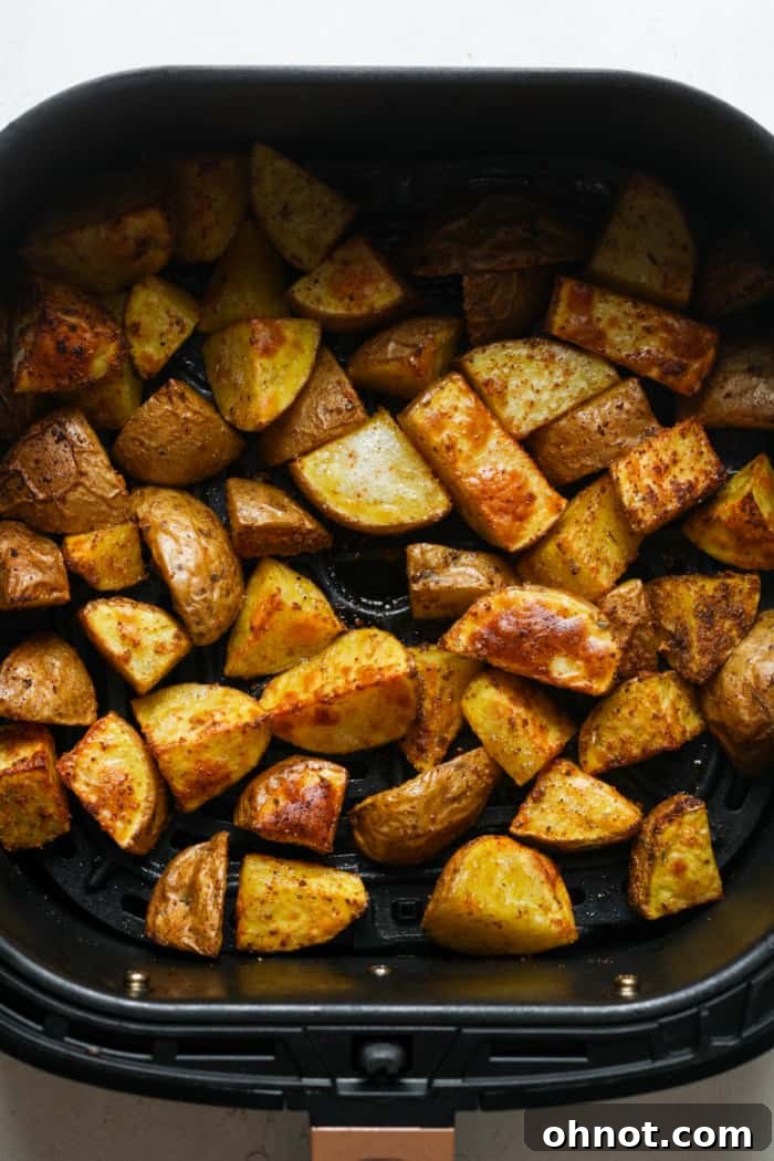 An air fryer basket filled with golden-brown, crispy home fries after cooking.