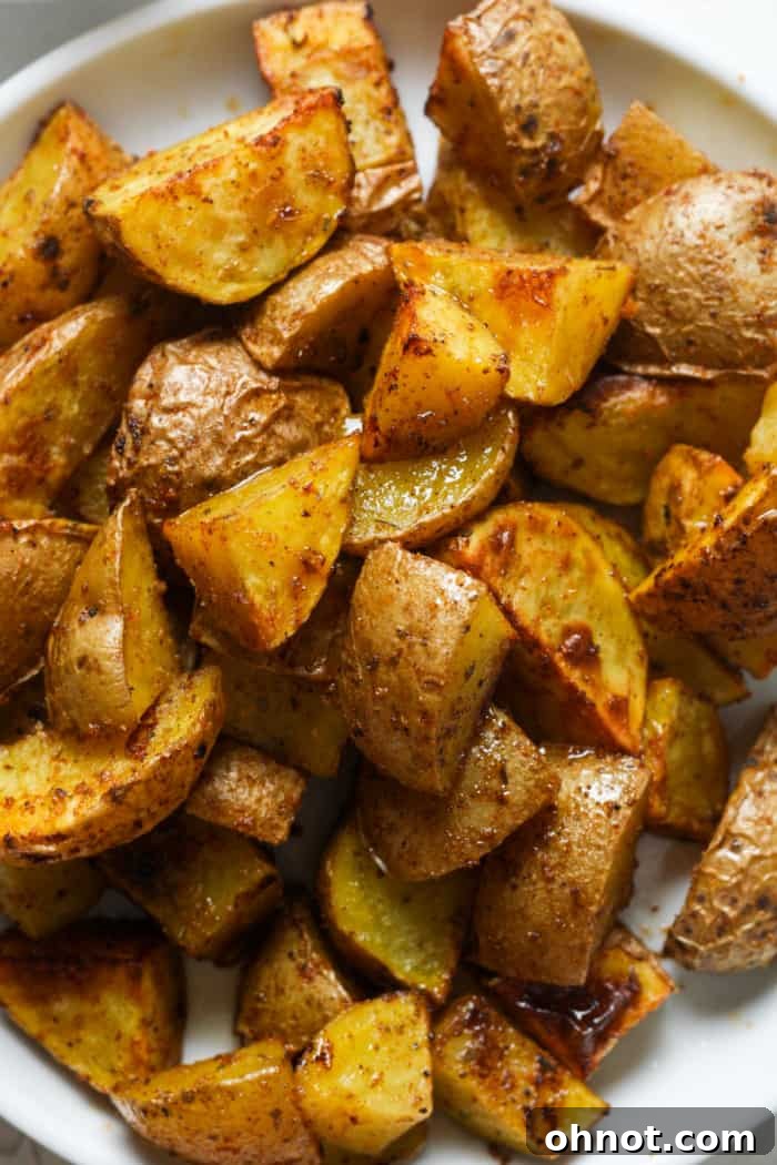 A simple white plate holding a serving of perfectly cooked air fryer home fries.