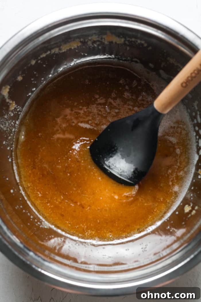 Oil, sugar, vanilla, and applesauce in a bowl.