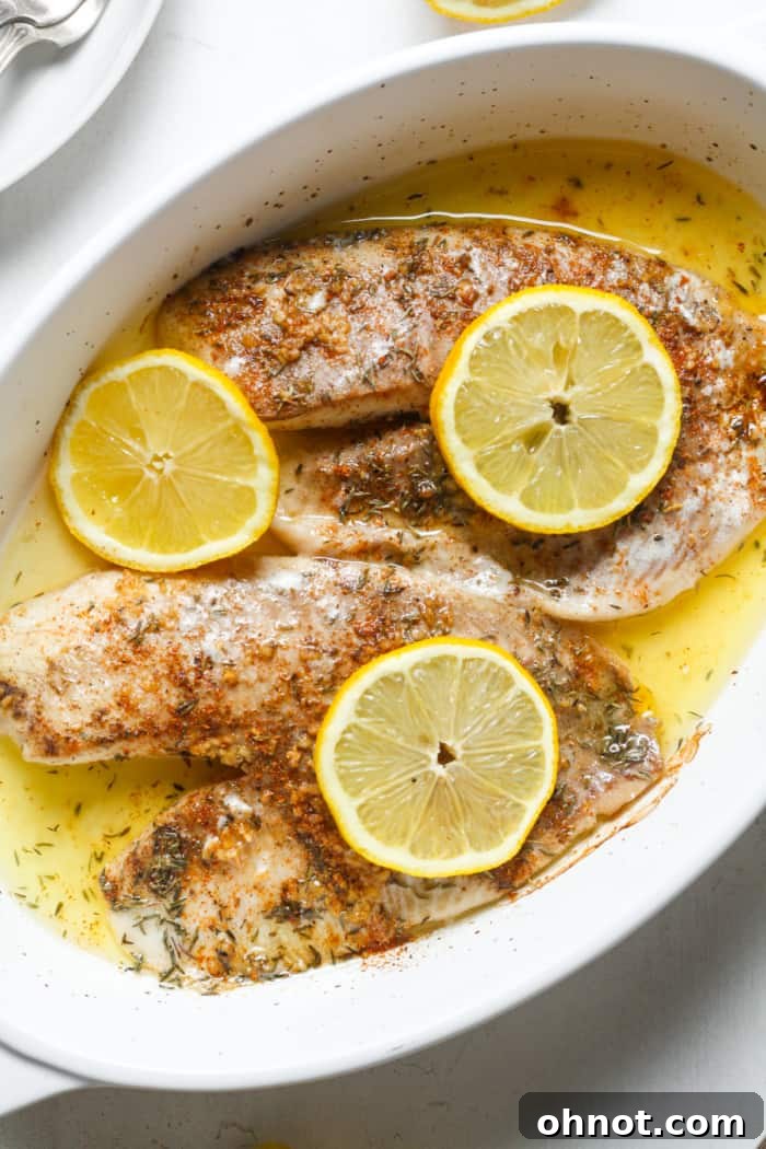 Delicious baked tilapia fillets seasoned with lemon, garlic, and herbs, served on a plate.