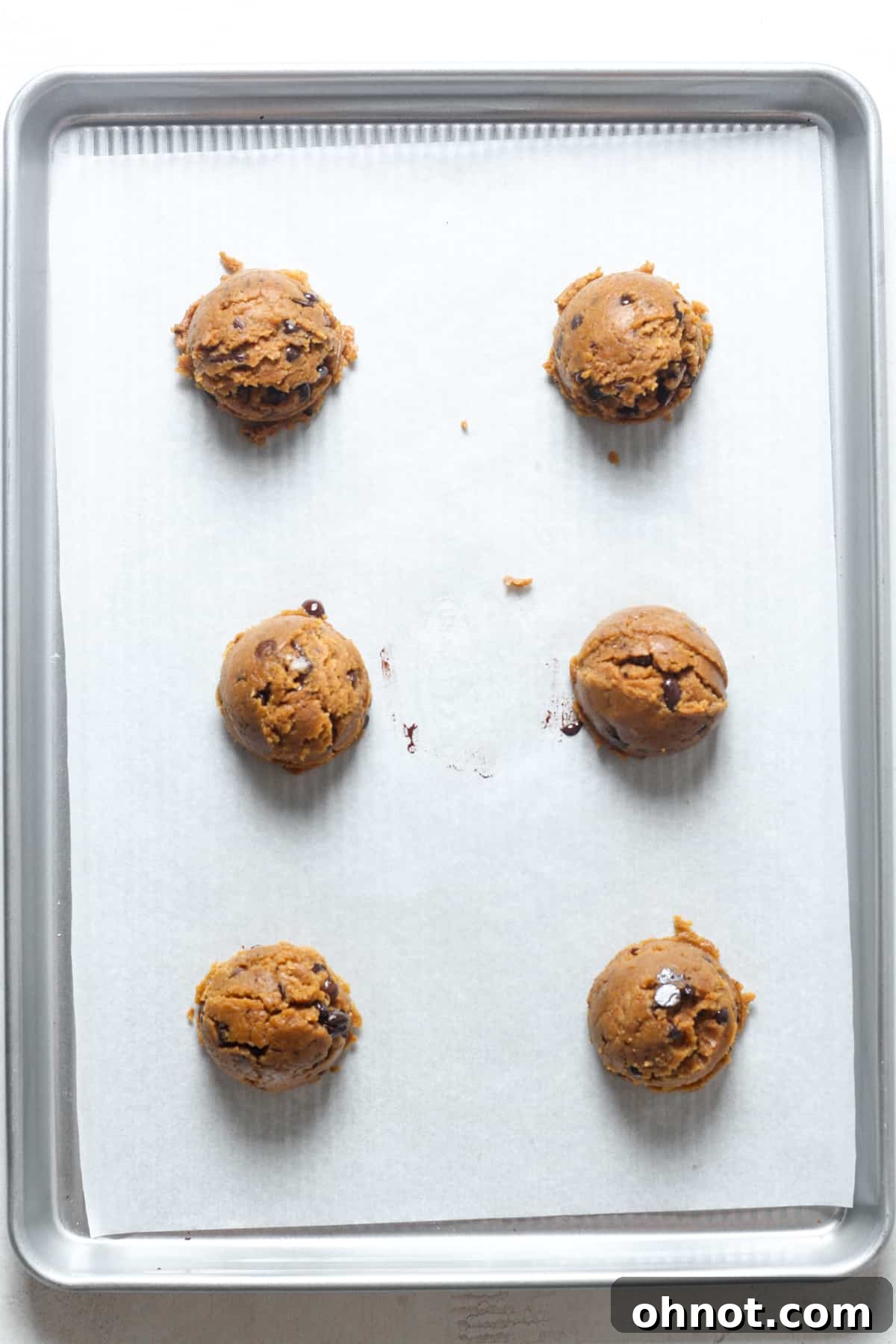 Scoops of pumpkin dough on a baking sheet.