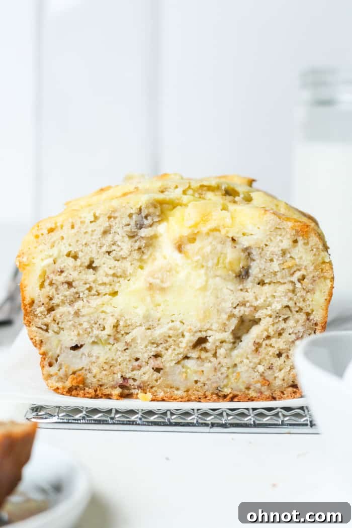 A slice of moist cream cheese banana bread showing the gooey swirl.