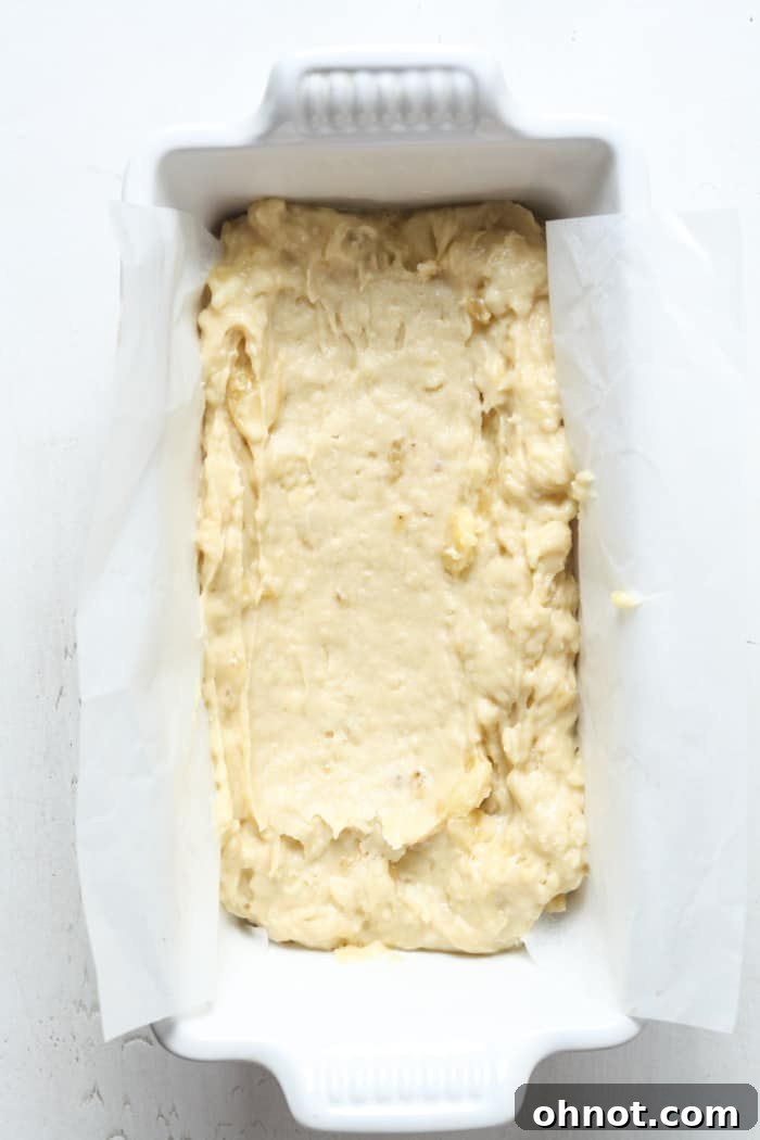 Half of the banana bread batter spread in a loaf pan.
