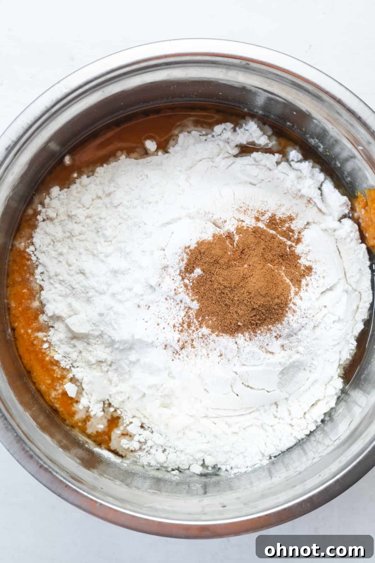Adding flour and spices to the wet pumpkin mixture.
