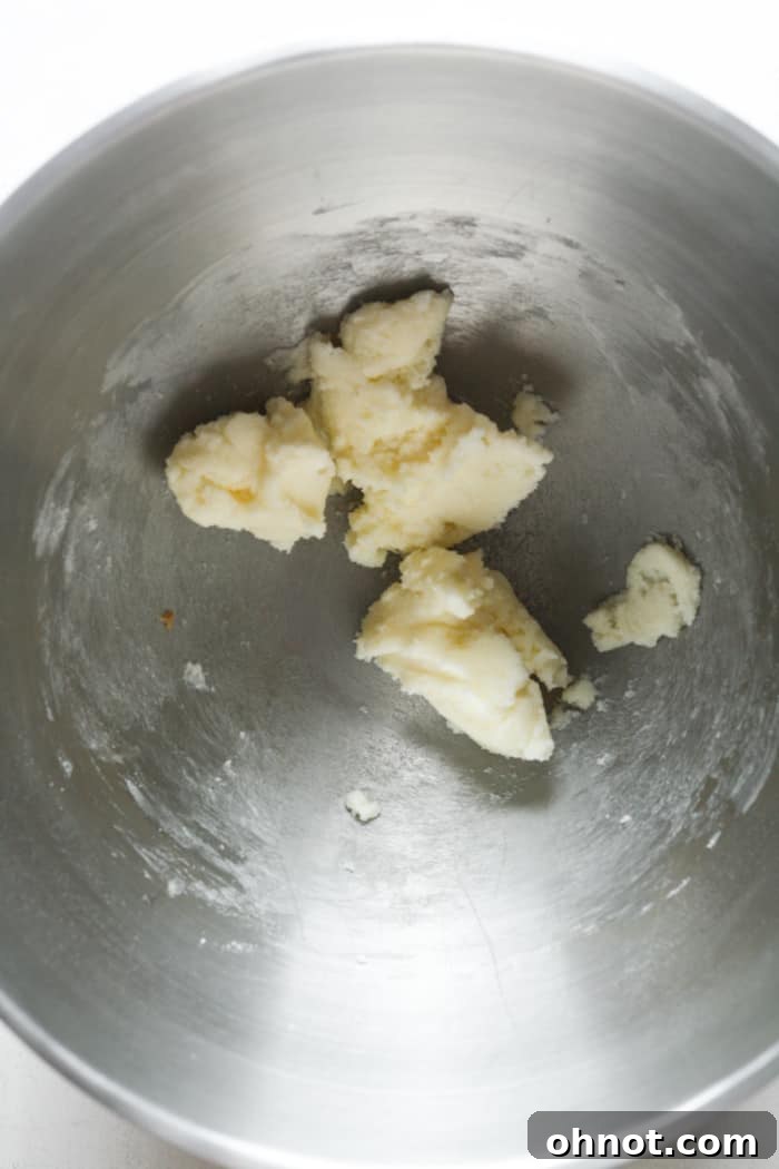 Close-up of butter and sugar being creamed together in a mixing bowl, forming a sandy dough.