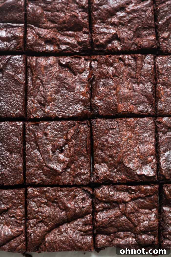 Freshly baked and sliced vegan brownies, showcasing their rich, fudgy interior and shiny top.