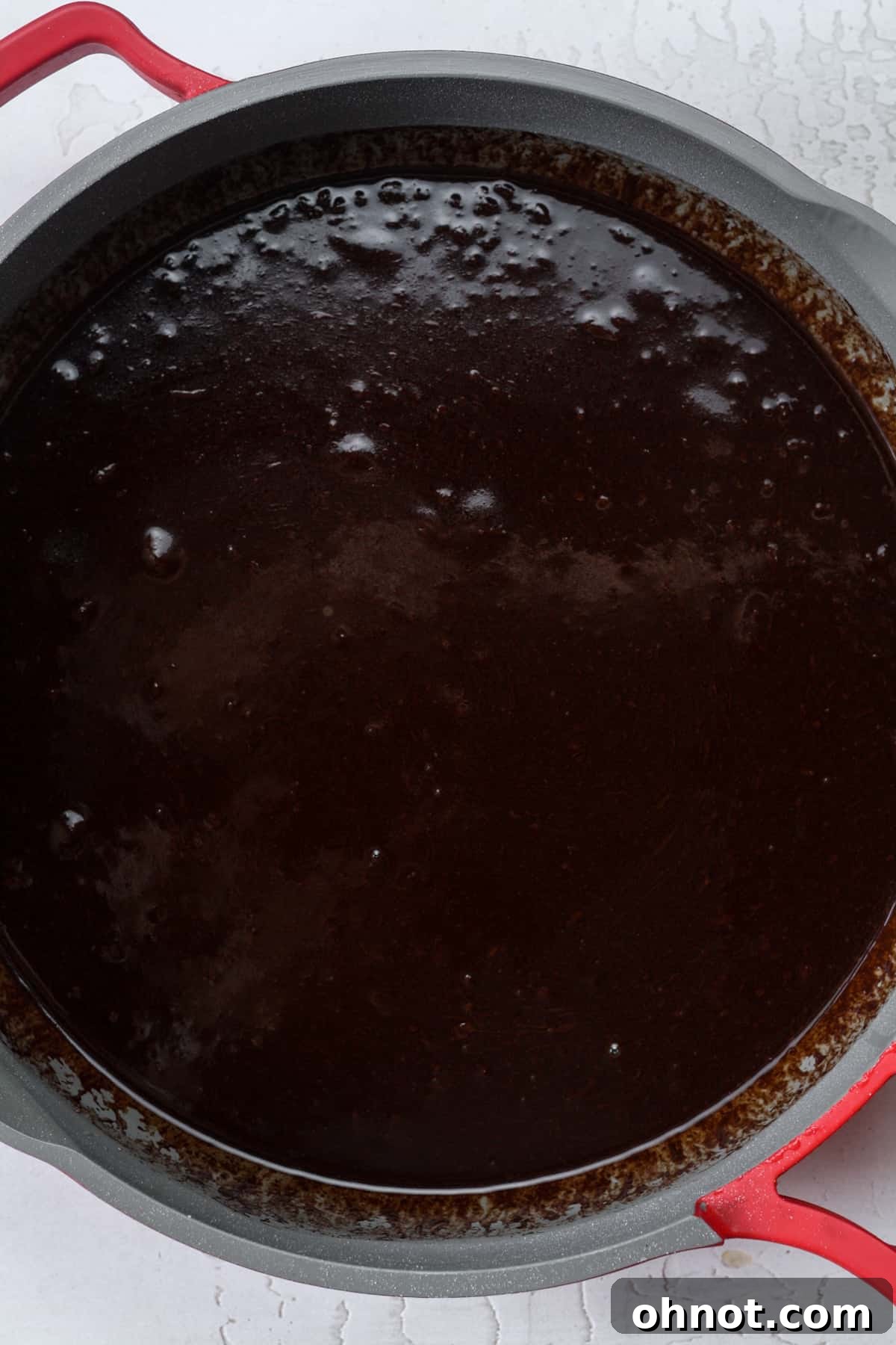 The chocolate, butter, and sugar mixture in the skillet, now fully melted and stirred into a smooth, shiny consistency.