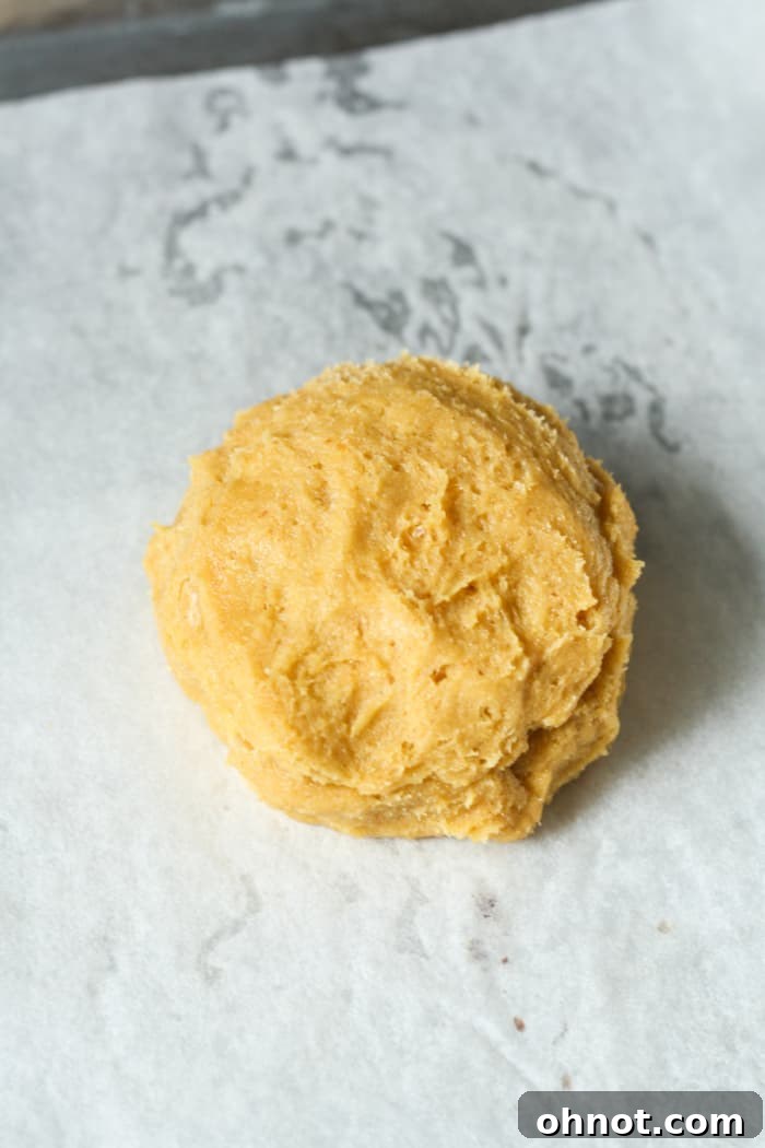 A perfectly round orange pumpkin cookie ball, ready for baking.