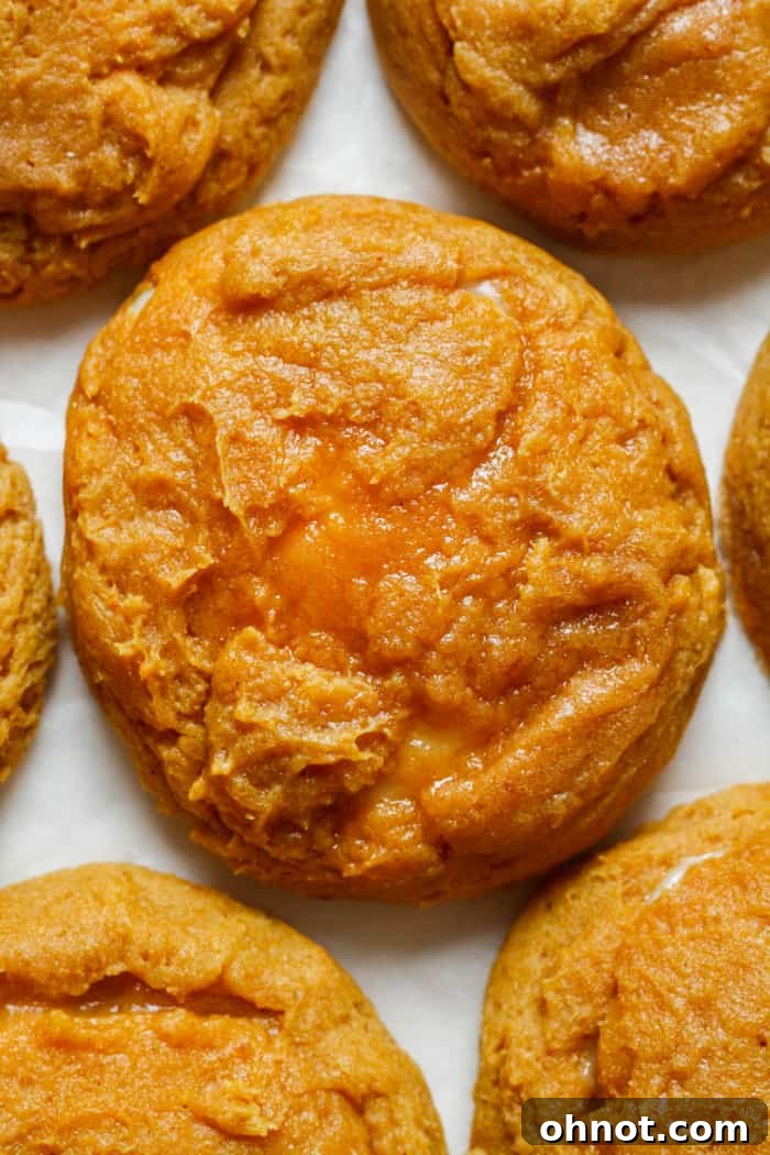 Close-up of a soft-baked pumpkin cheesecake cookie, revealing its gooey cream cheese center.