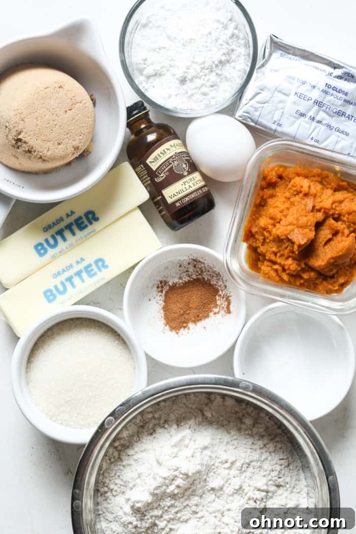 Assortment of fresh baking ingredients including pumpkin puree, spices, flour, and butter, ready for making pumpkin cheesecake cookies.