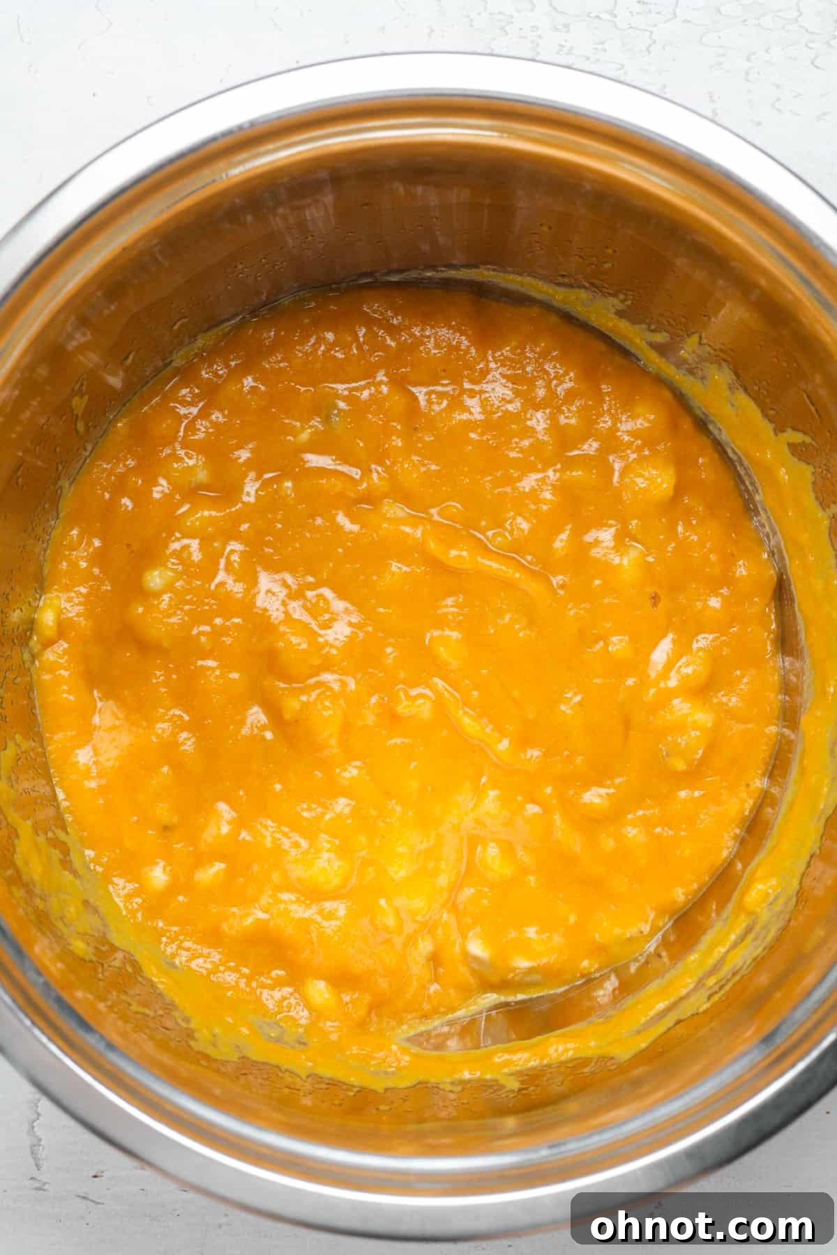 A light orange, smooth wet batter mixture in a bowl, perfectly combined for baking.