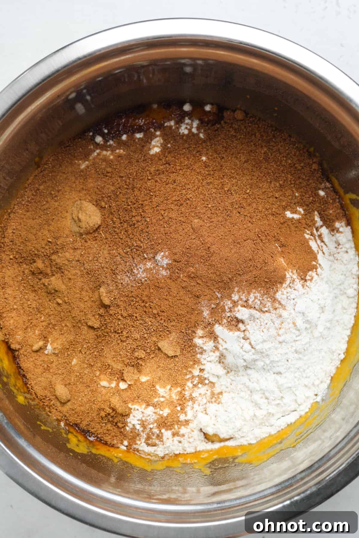 Dry ingredients, including coconut sugar and flour, being added to the wet mixture in a bowl.
