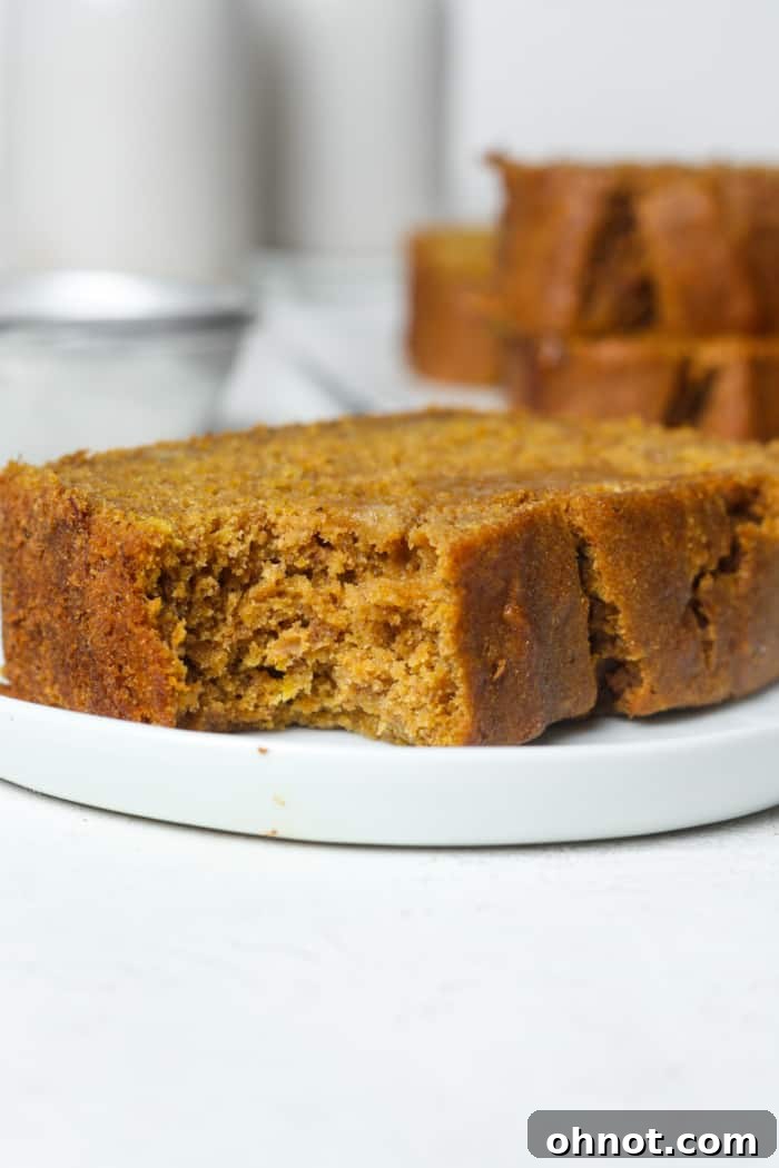 A slice of warm pumpkin banana bread with a bite taken out, revealing its moist, fluffy interior.