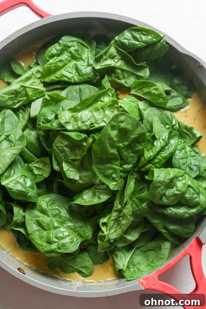 Wilted spinach mixed into the creamy butternut squash curry in the pan.