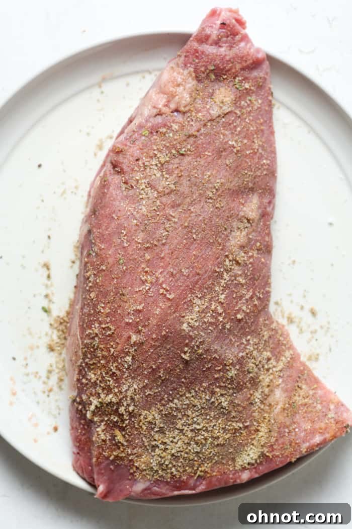Tri tip steak generously seasoned on a plate.