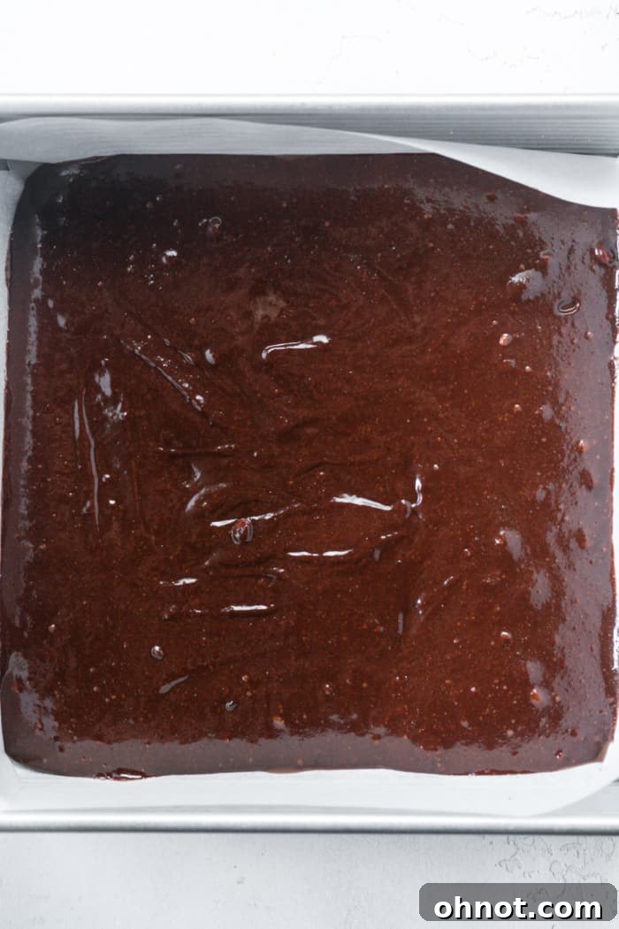 First layer of brownie batter spread evenly in a square pan.