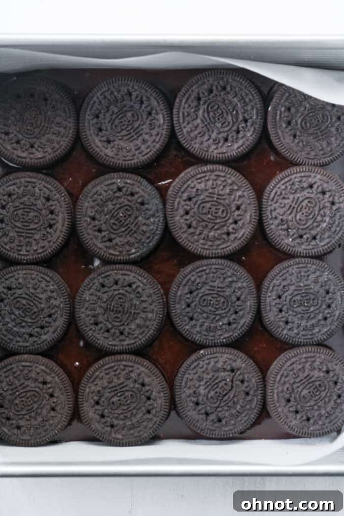 Whole Oreos placed in a grid pattern on top of the first layer of brownie batter.