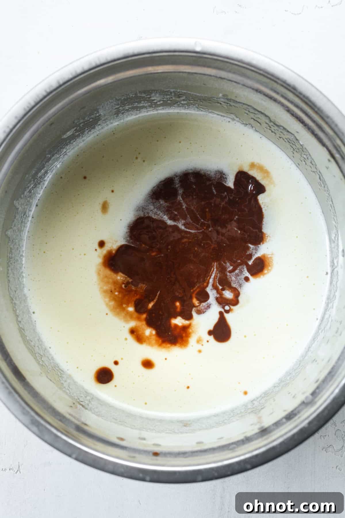 Melted chocolate mixture being added to the sugar and egg mixture.