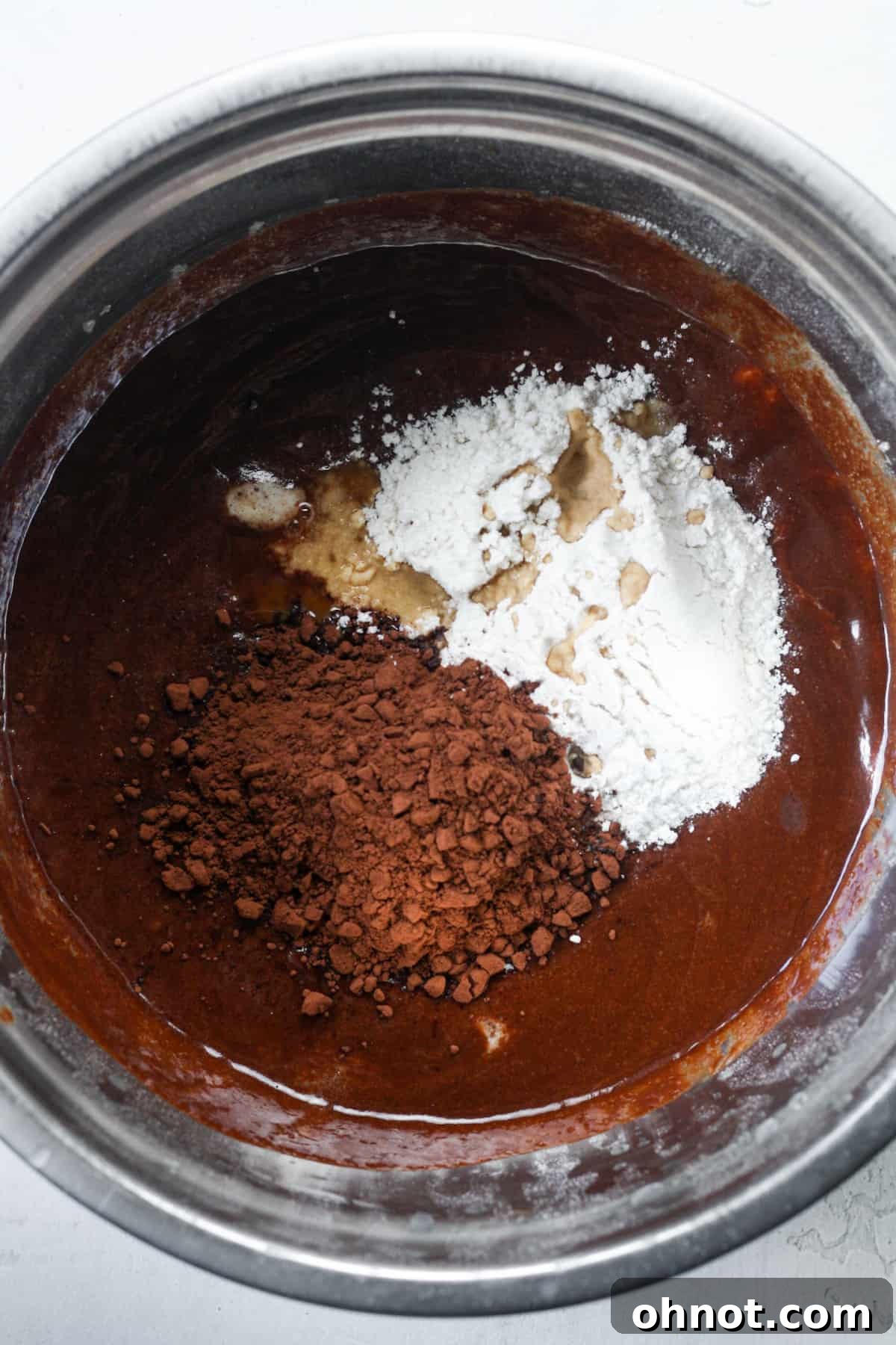 Dry ingredients, including flour and cocoa powder, added to the brownie batter.