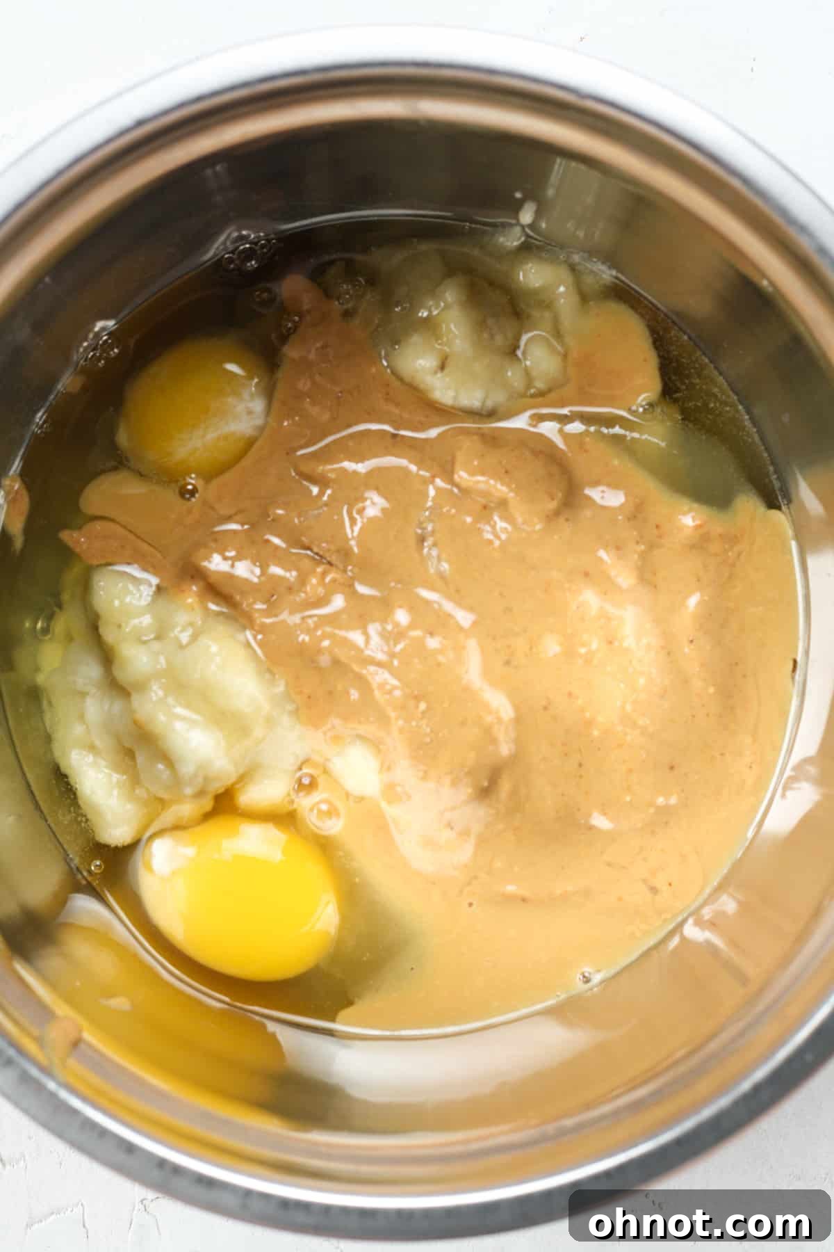 Eggs and nut butter in a mixing bowl, ready to be combined with mashed bananas.