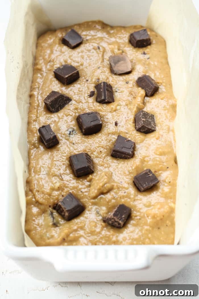 Protein banana bread batter in a parchment-lined loaf pan, ready for baking.