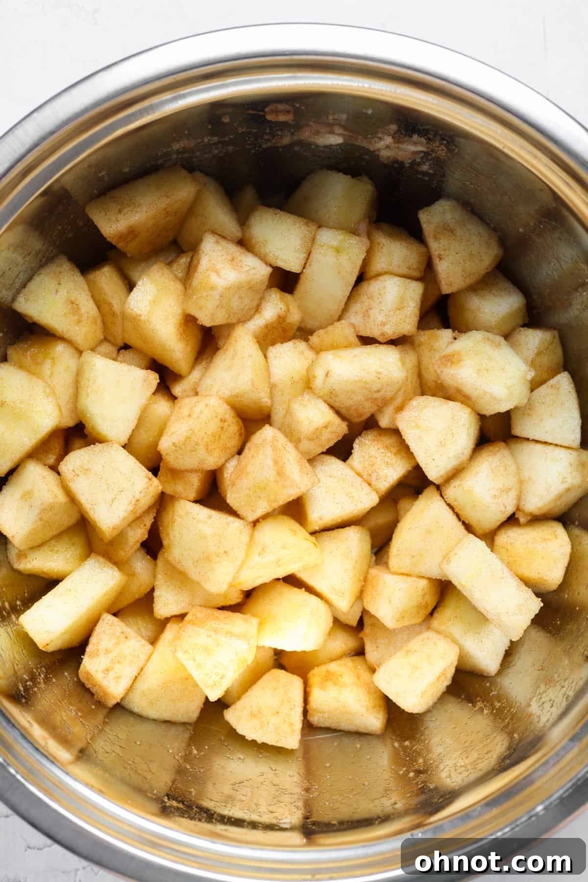 Close-up of cinnamon-sugar coated apple cubes, glistening and ready for baking.