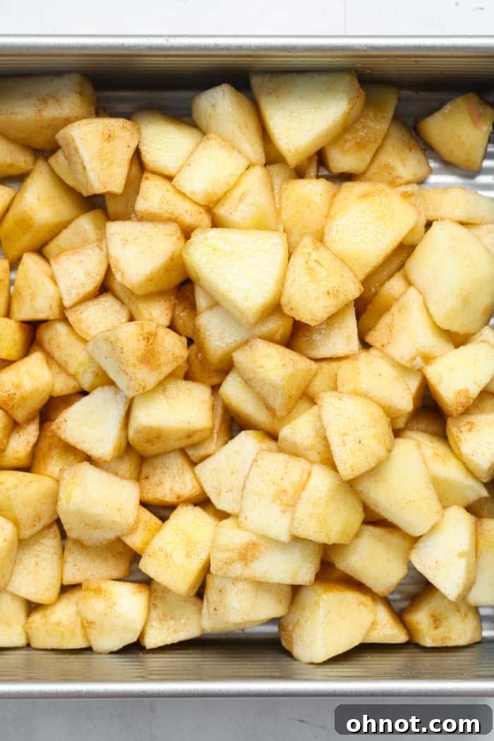 Evenly spread cubed fruit in a baking pan, ready for the topping.