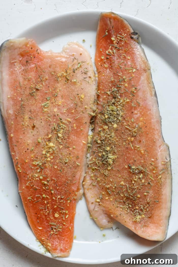Trout fillets seasoned with a blend of garlic, pepper, salt, oregano, and thyme on a plate.
