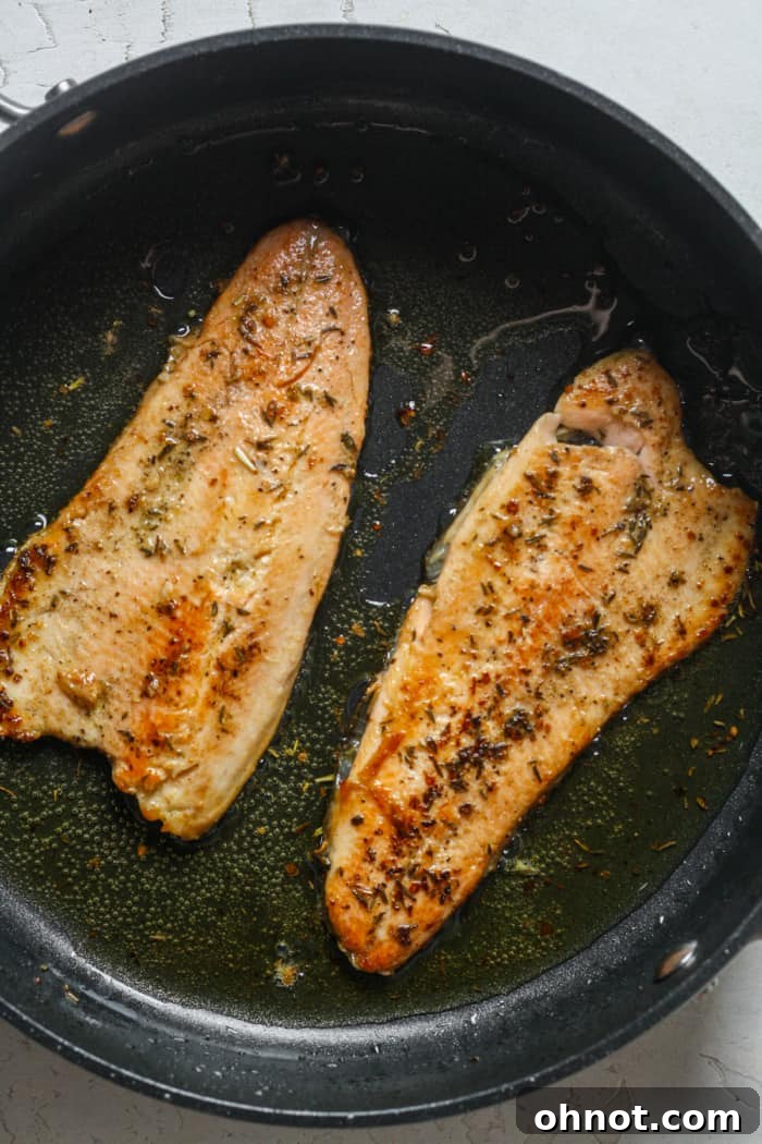 Fried trout fillets, flipped in the skillet, with fresh lemon juice being squeezed over them.