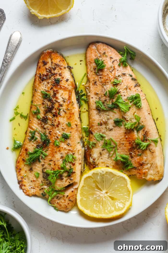 Healthy trout dish served with garlic sauce, parsley, and lemon wedges.